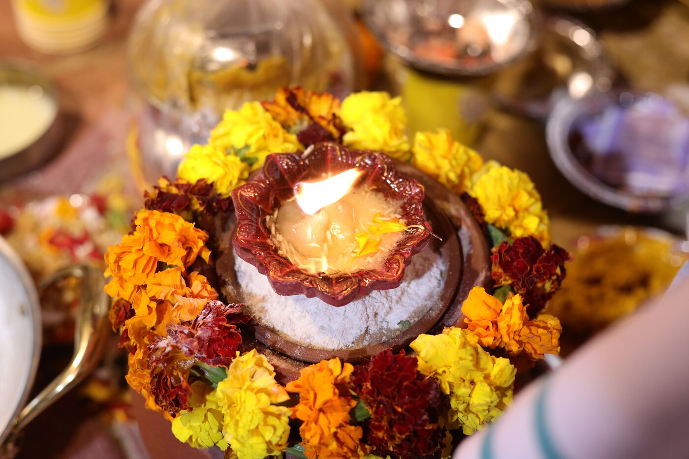 Sacred diya surrounded by marigold flowers during a Hindu ritual